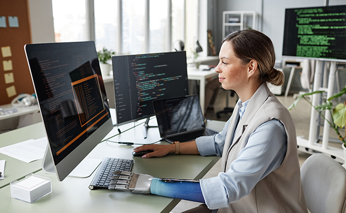 Une femme avec un bras prothétique travaillant sur de la programmation informatique