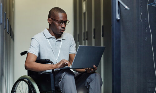 Man in wheelchair working on laptop in backend office