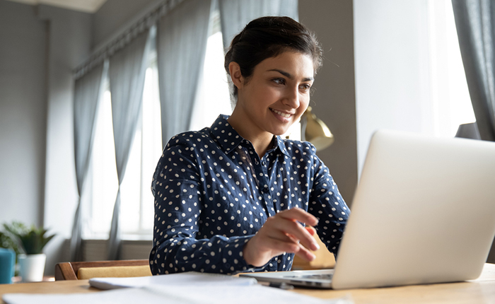 Une femme souriante travaillant sur un ordinateur portable à un bureau