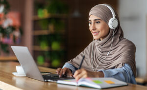 Woman wearing headphones listening to webinar on laptop