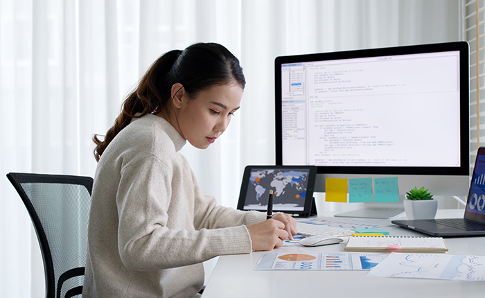 Business woman working at a desk in front of two computer screens