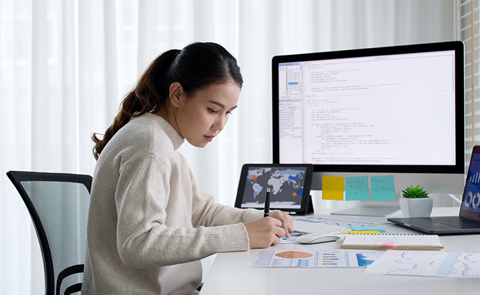 Business woman working at a desk in front of two computer screens