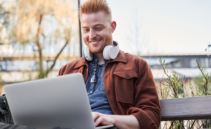 Man sitting outside, working on laptop.
