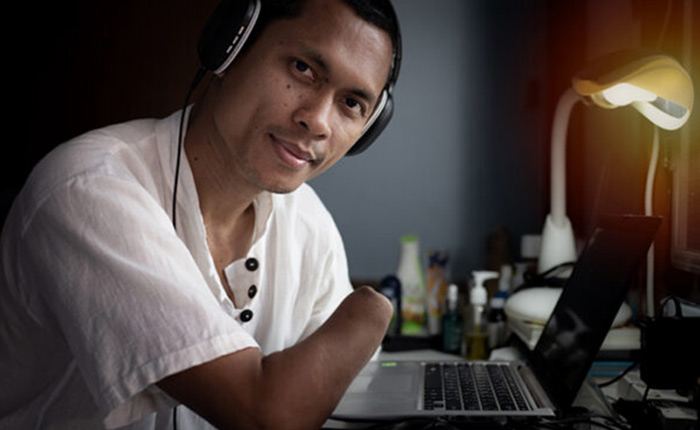Man with a residual limb working on the computer at his desk.